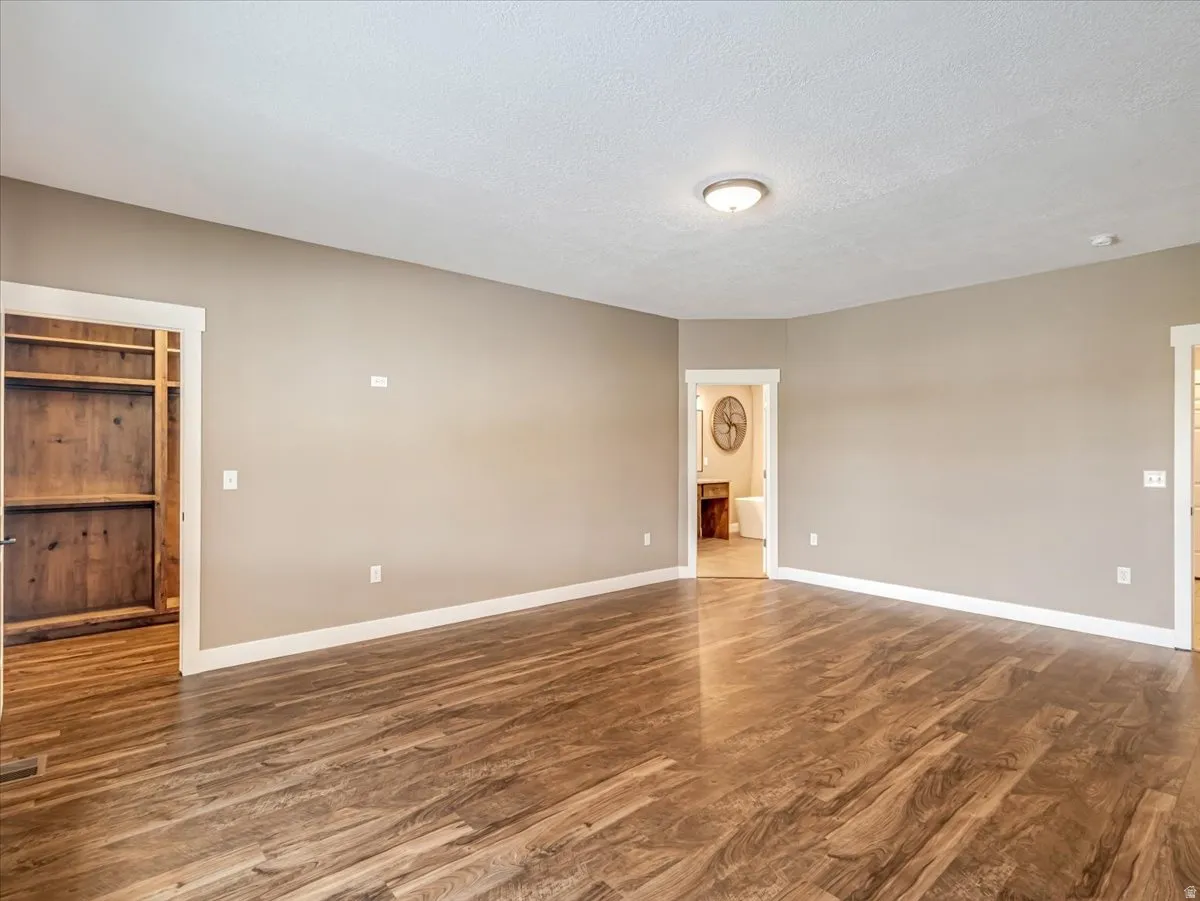 Spacious interior room featuring wood-finish flooring, neutral wall tones, and white baseboards