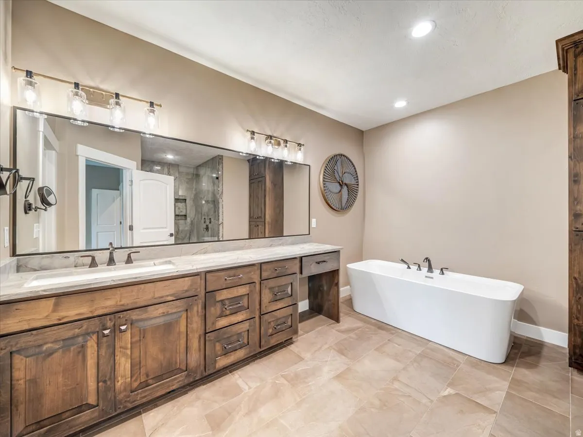 Expansive bathroom featuring a dual vanity with wood cabinetry, light-toned countertop, and undermount sinks