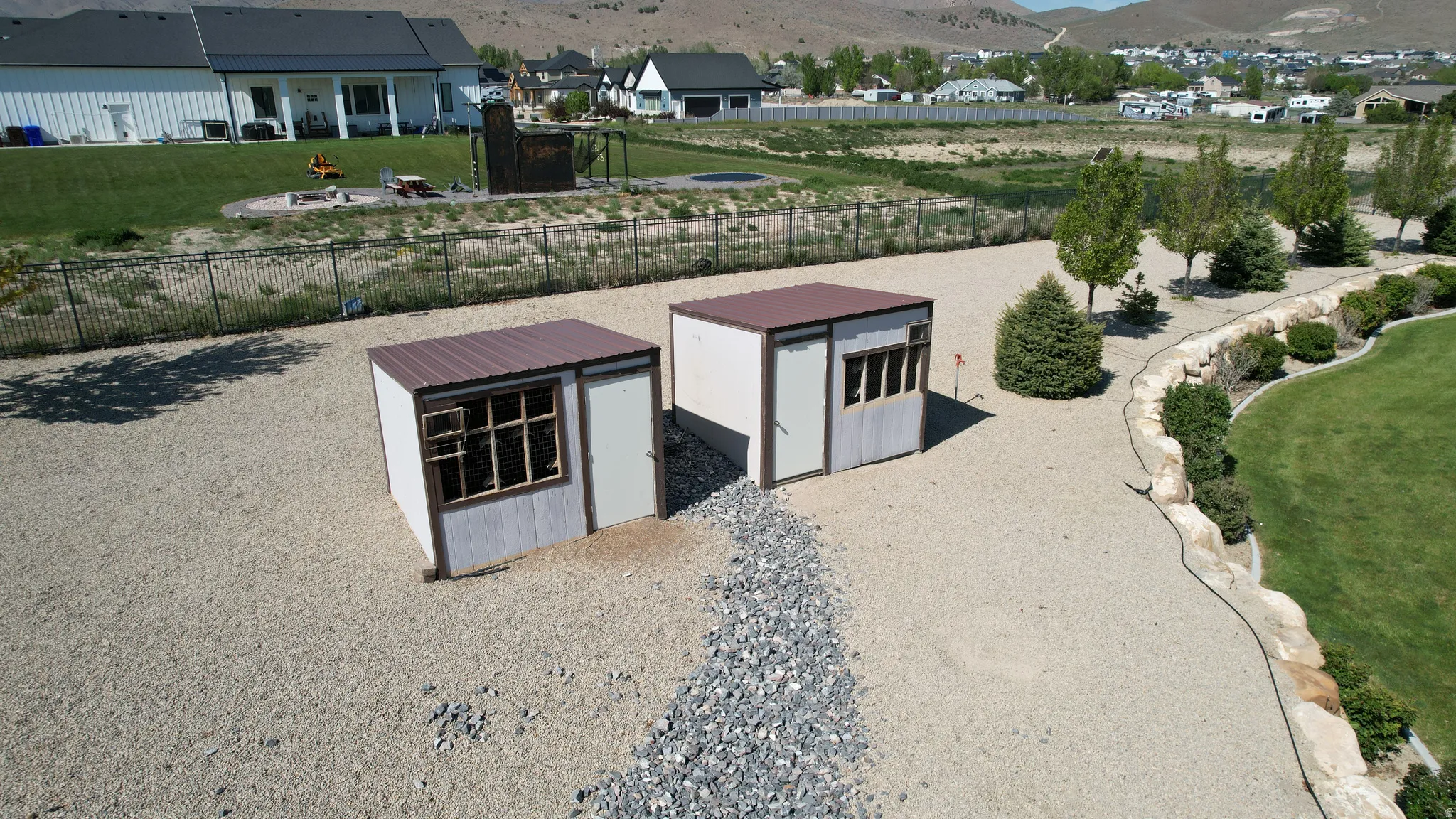 Two detached storage sheds with windows and side entries, set on a gravel base