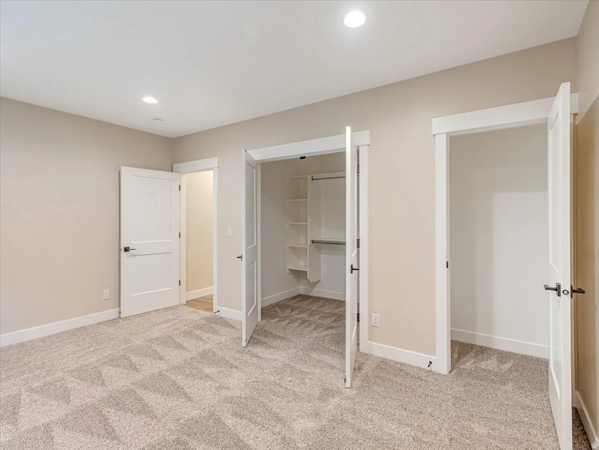 Neutral-toned room featuring a patterned carpet, recessed lighting, and multiple panel doors with matte black hardware