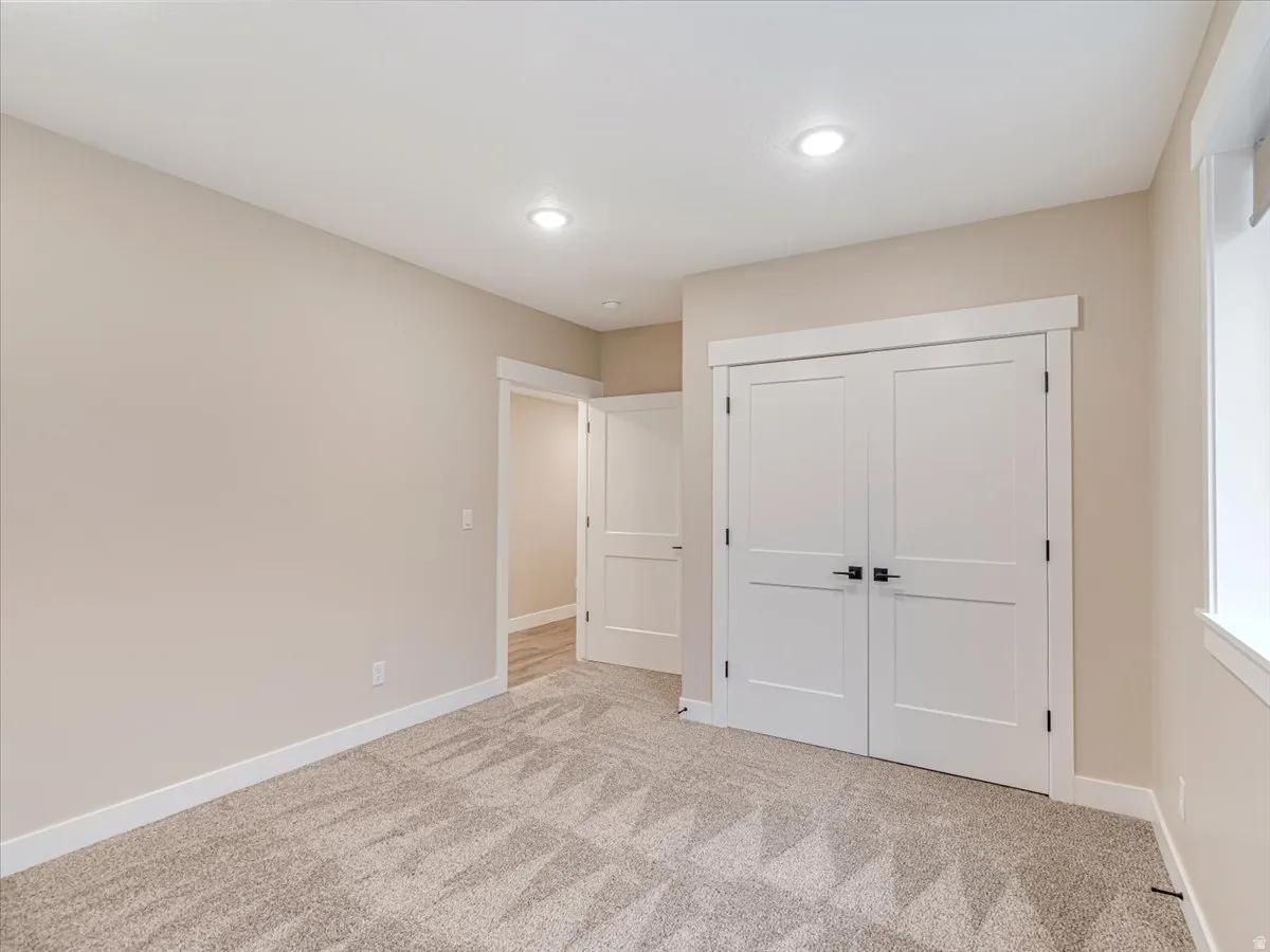 Room featuring light beige walls, recessed lighting, white baseboards, and patterned carpeting
