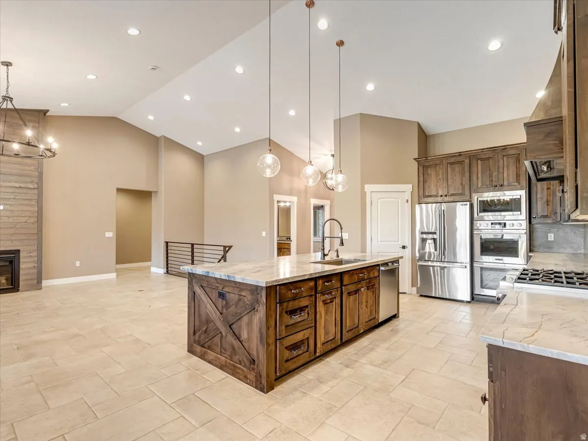 Spacious kitchen featuring a large wood-finish island with a stone countertop, stainless steel appliances, pendant lighting, and recessed ceiling lights