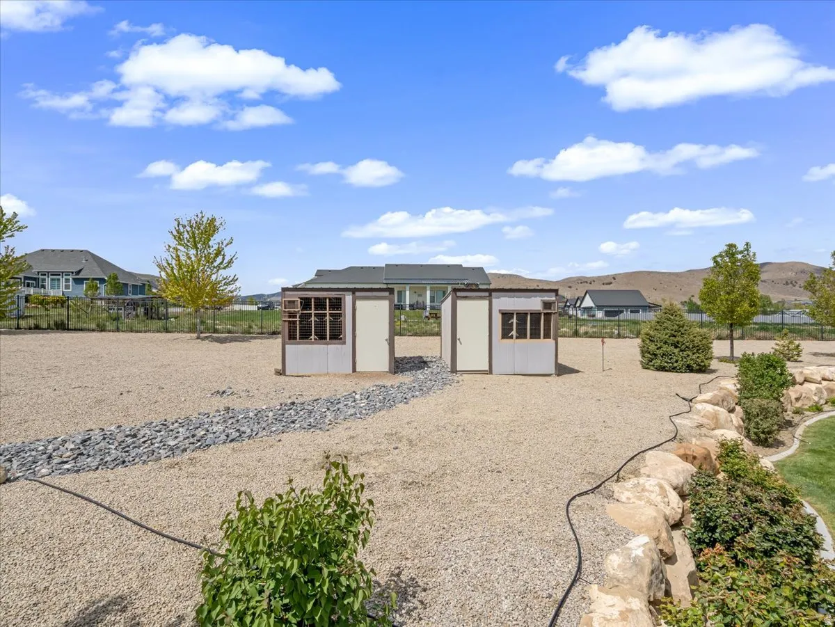 Gravel backyard featuring two sheds, a decorative rock path, and a stone retaining wall