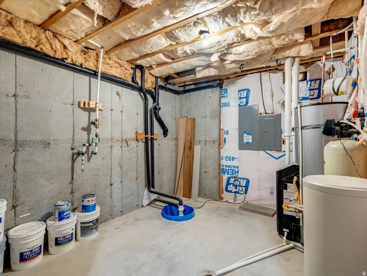 Unfinished basement with concrete walls, exposed ceiling joists, insulation, and visible plumbing