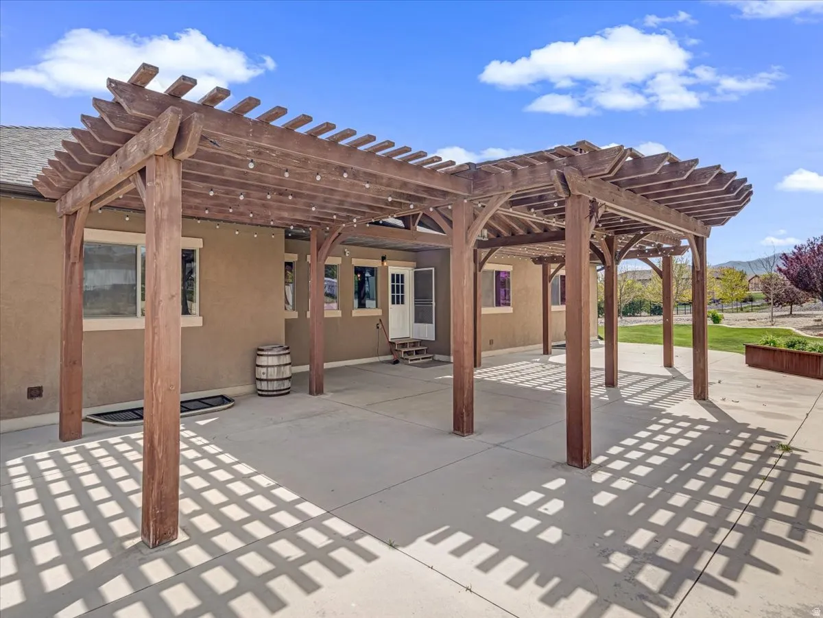 Expansive concrete patio featuring a large wooden pergola