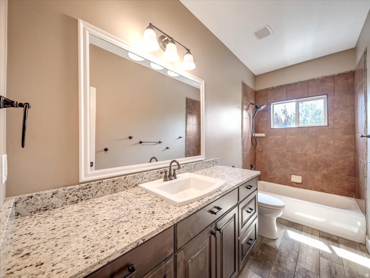 Modern vanity with a light-toned granite countertop, undermount sink, and dark wood-finish cabinetry