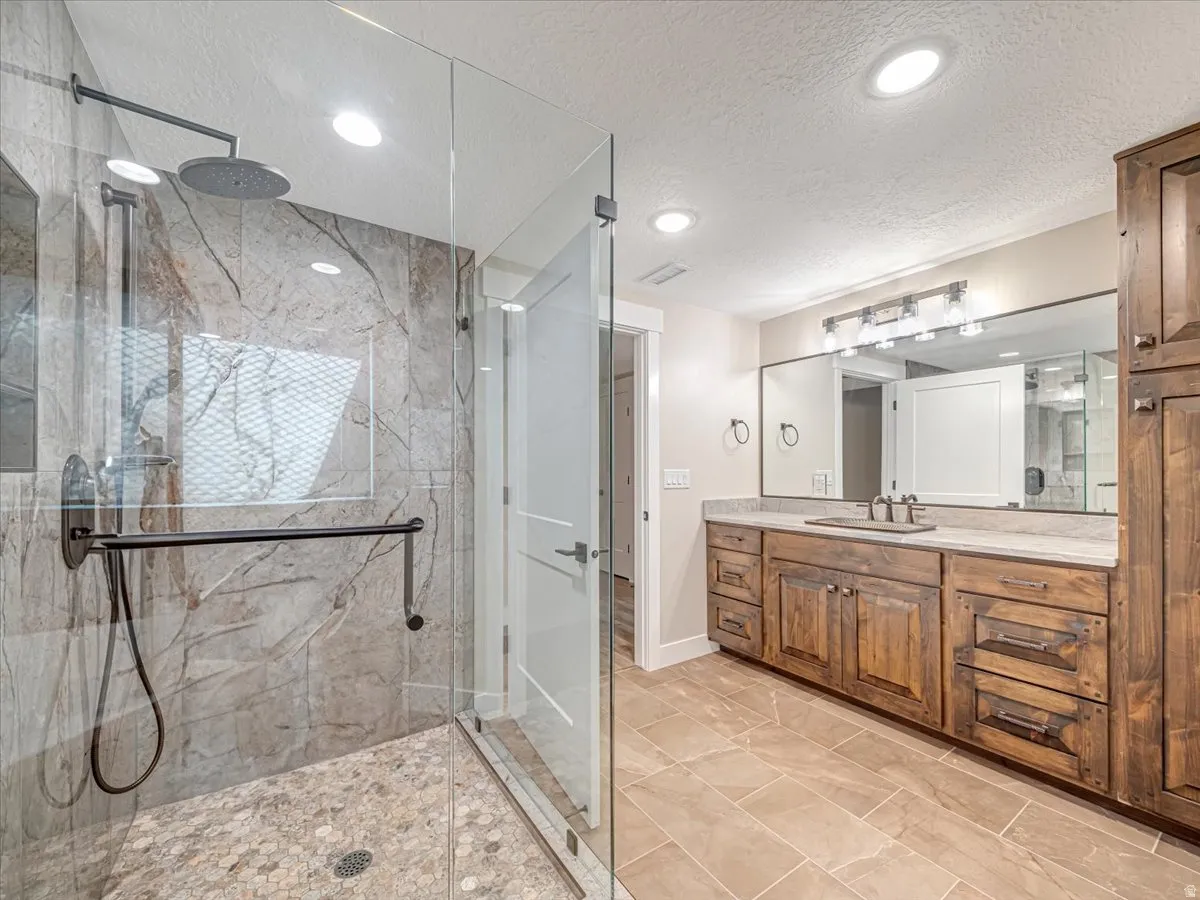 Spacious bathroom featuring a glass-enclosed shower with a rain shower head and a handheld shower fixture