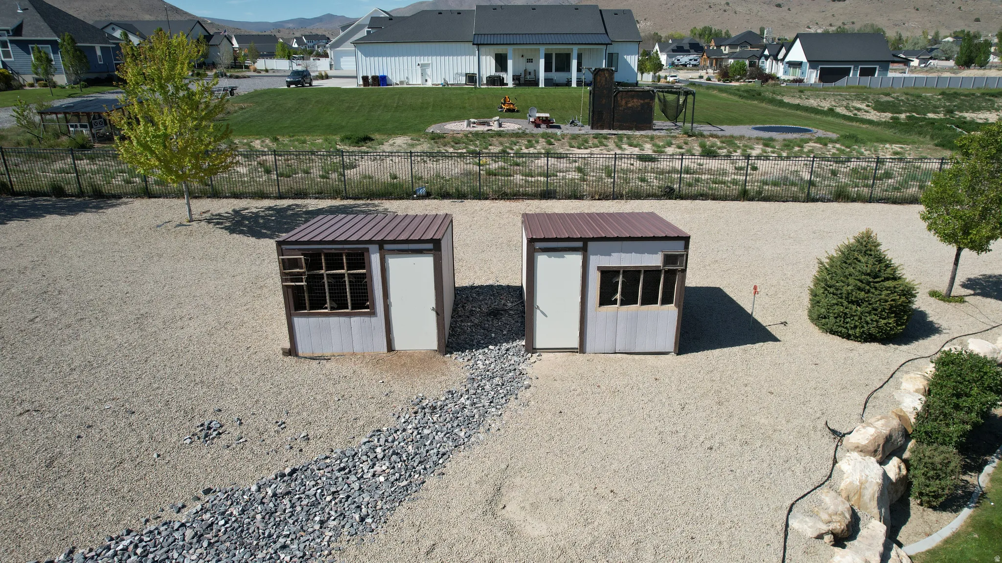 Two matching outbuildings with corrugated metal siding and brown roofs, set within a gravel-covered property