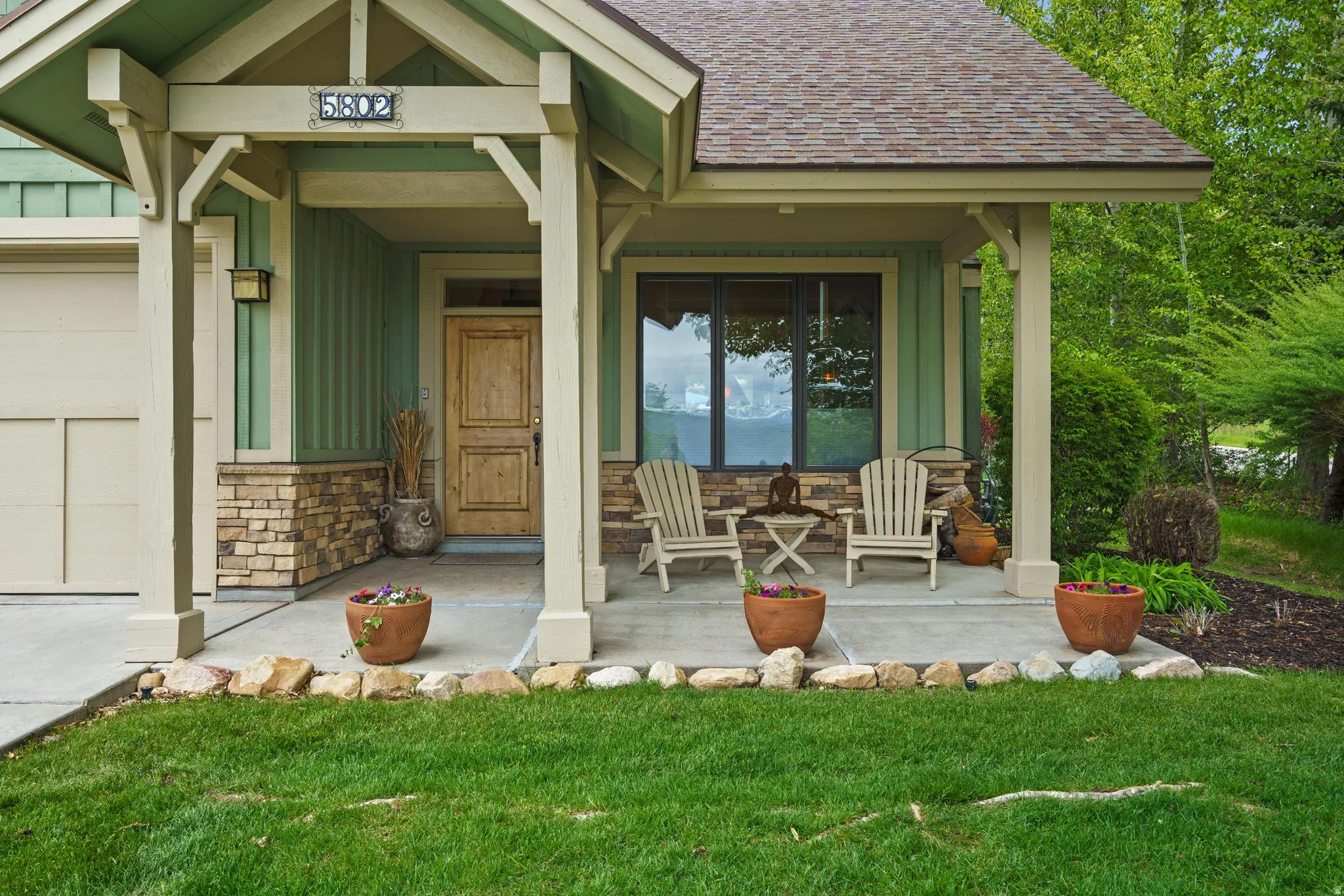 Front Entrance with a covered front porch, vertical siding, stone veneer accents.