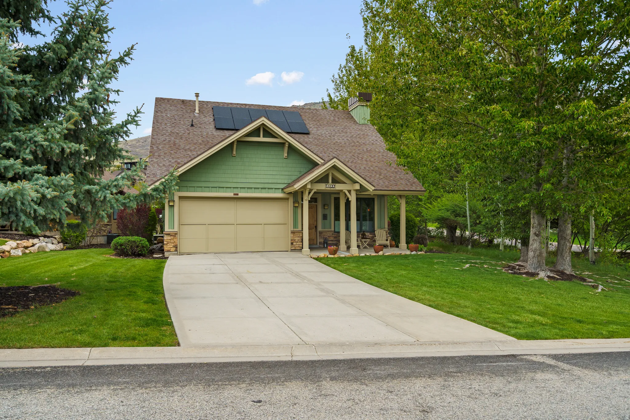 Front exterior with a two-car garage, covered porch entry, and visible solar panels