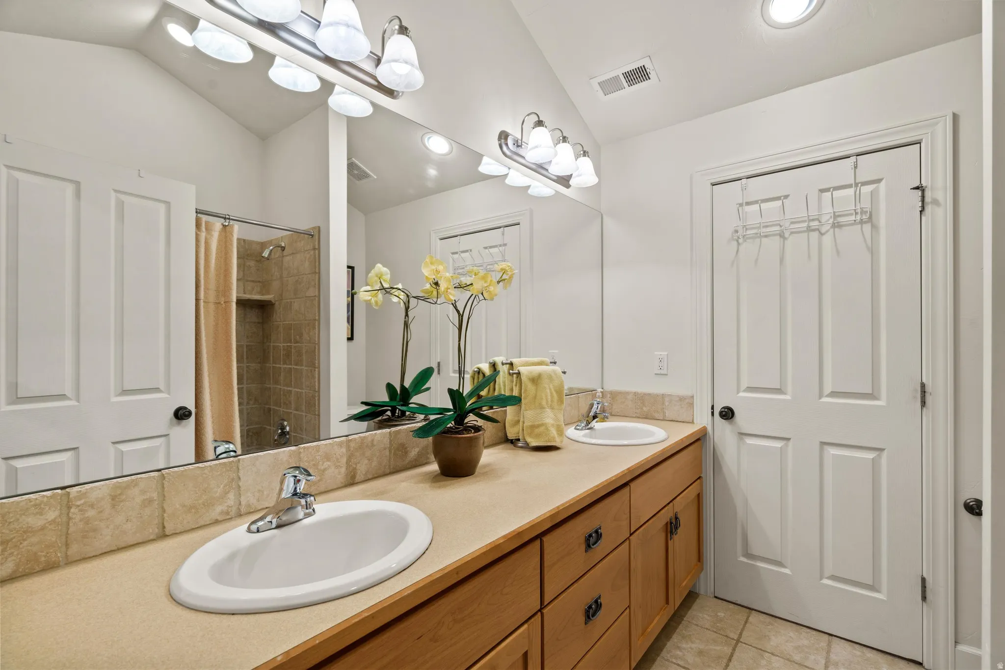 Dual vanity with integrated sinks, light wood-finish cabinetry, and a beige countertop