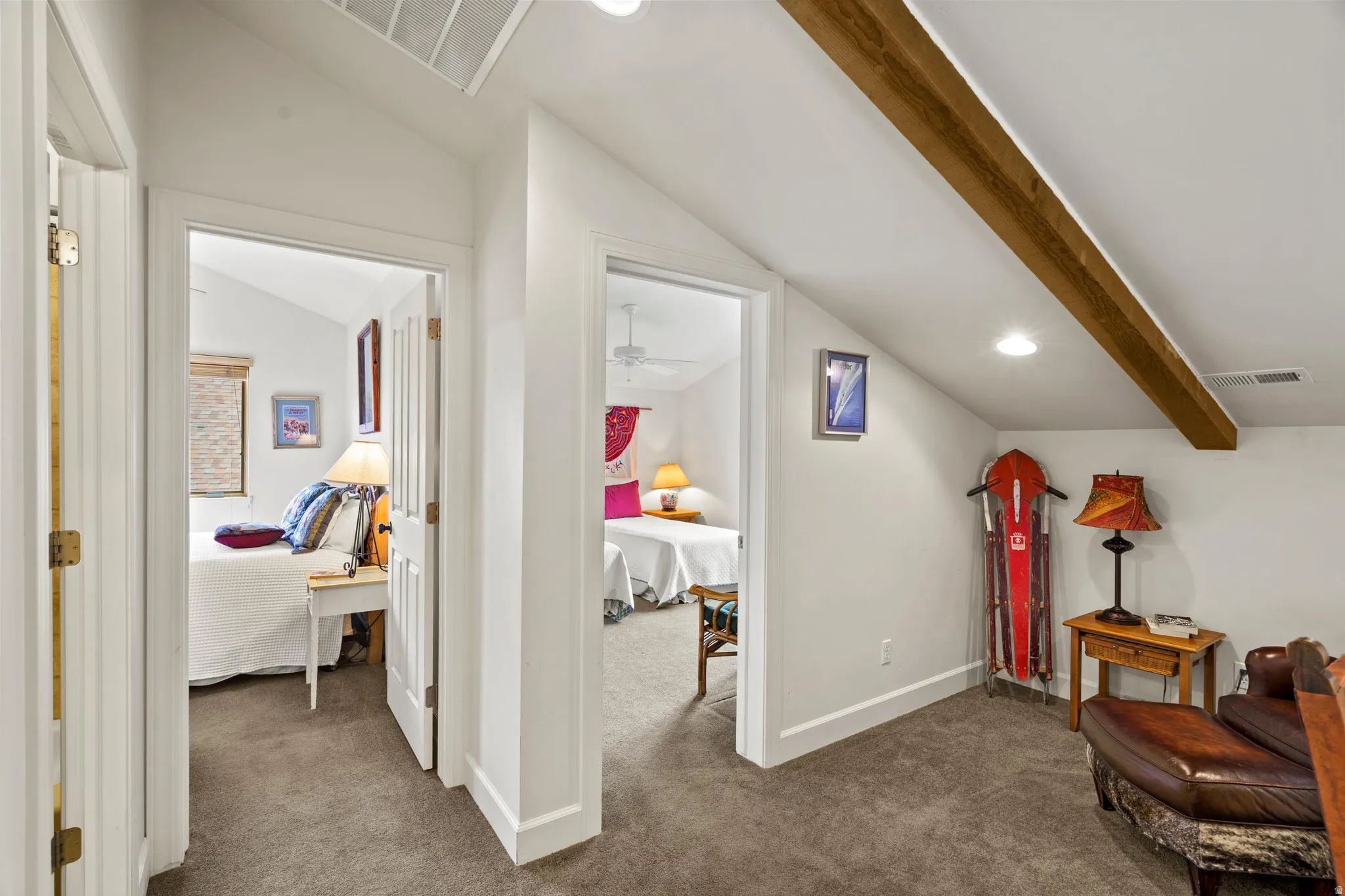 Carpeted hallway featuring vaulted ceilings, recessed lighting, and an exposed wood beam