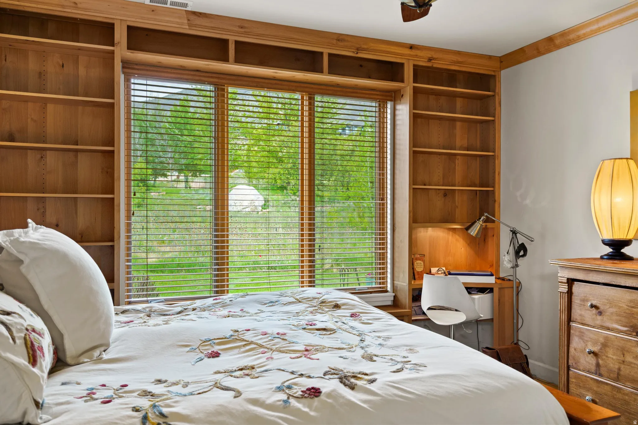 Built-in wood shelving and desk area with window overlooking exterior greenery