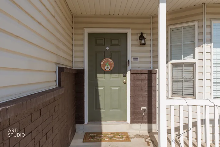 Front entrance featuring a paneled door, horizontal siding, and a brick base