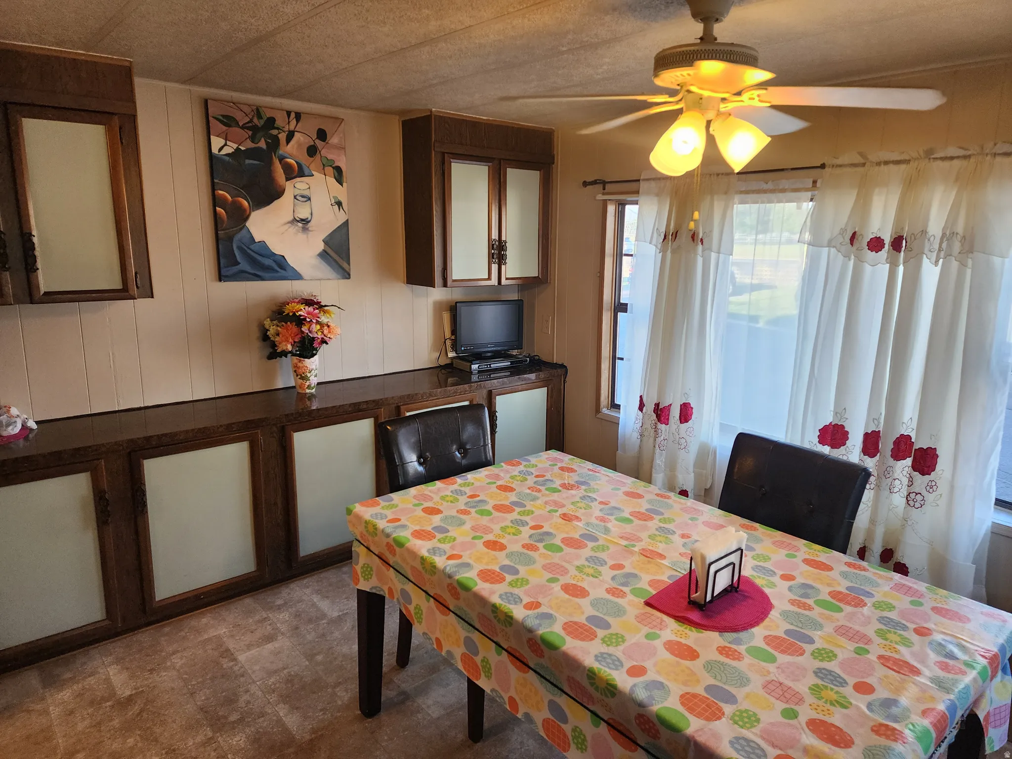 Dining area featuring wood-finish flooring, built-in cabinetry with frosted glass panels, and a ceiling fan with integrated lighting
