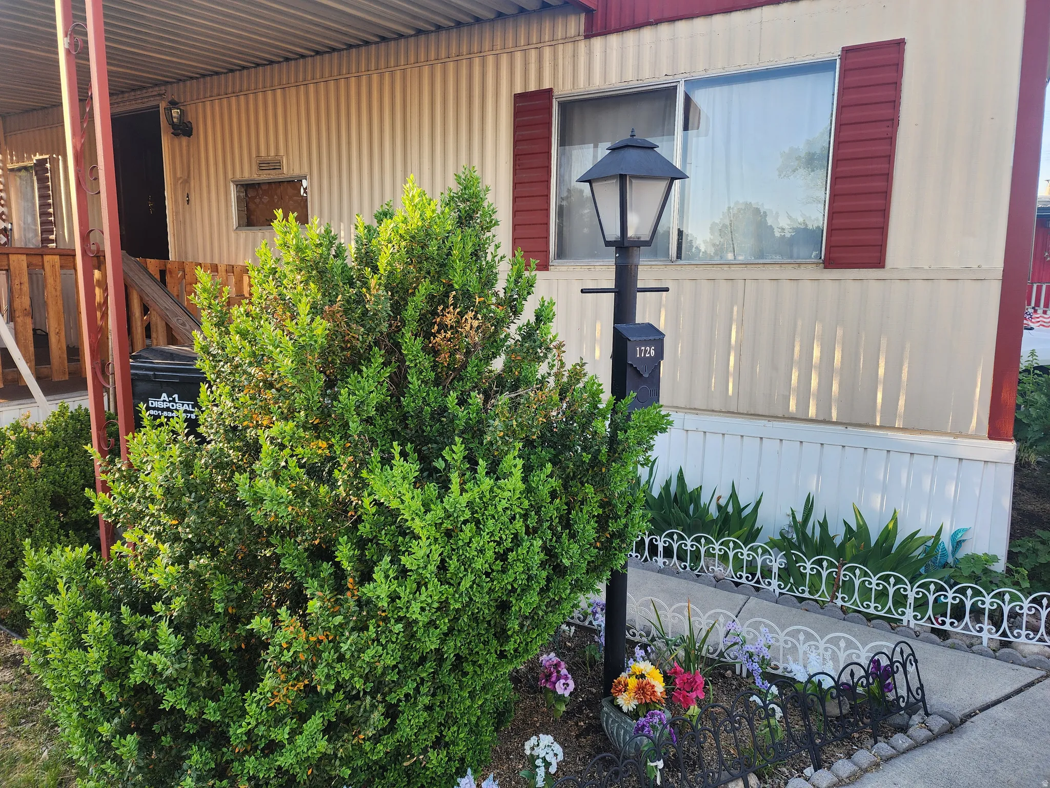 Front exterior featuring horizontal panel siding, a window with red shutters, and a decorative lamppost with an integrated mailbox