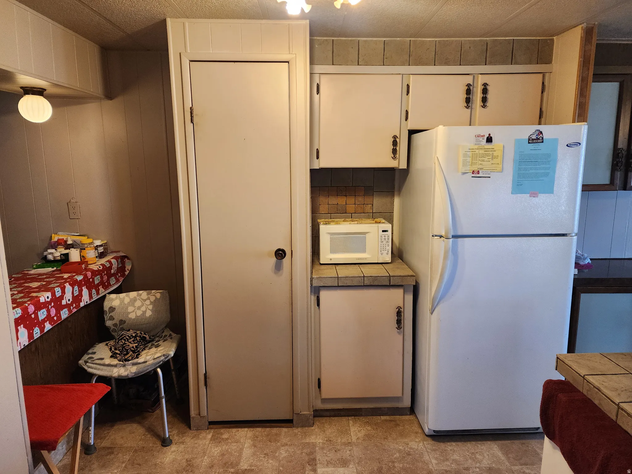 Functional kitchen area featuring upper and lower cabinetry, a tile backsplash, and durable vinyl flooring