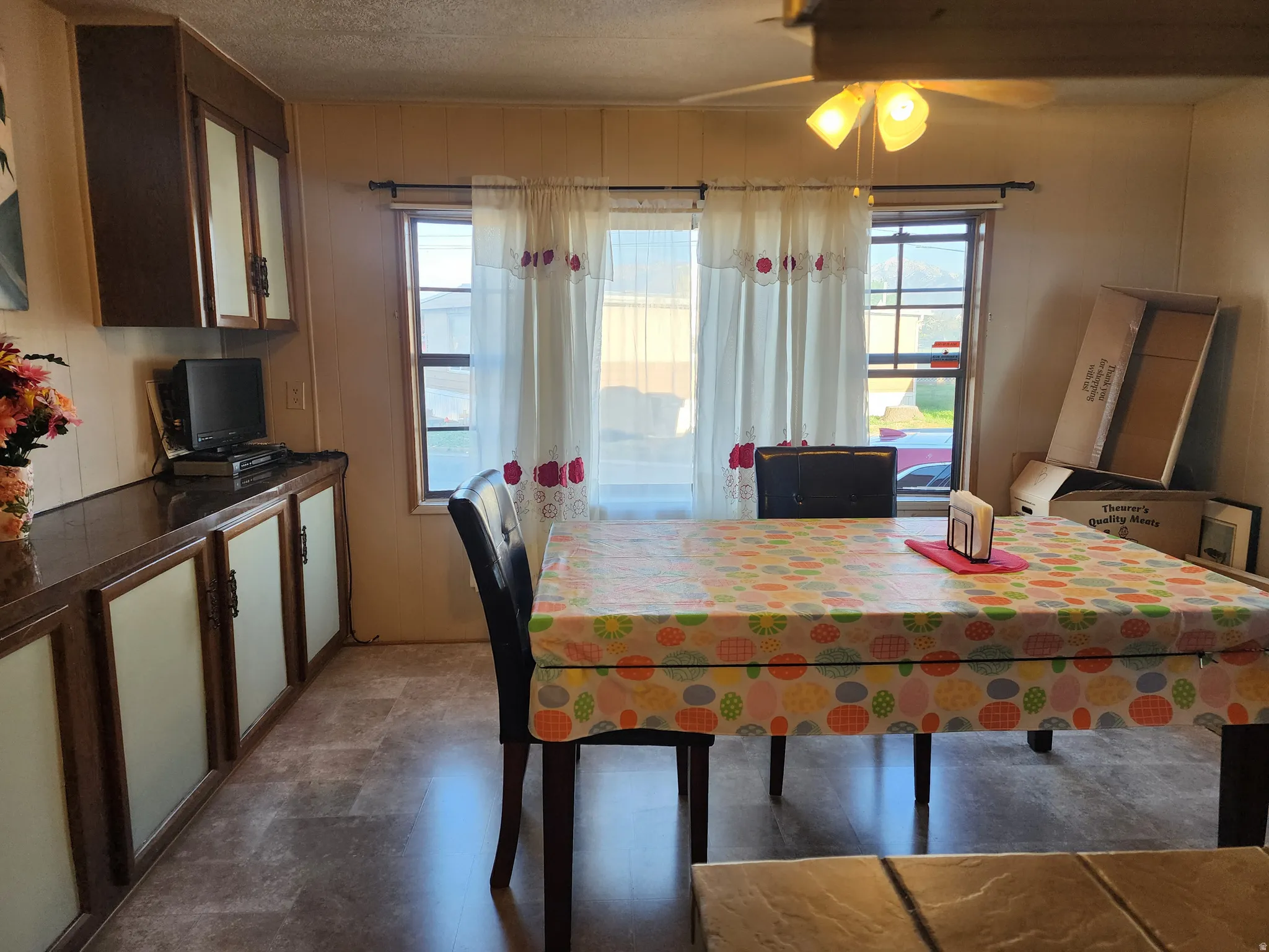 Dining area featuring wood-finish flooring and two windows with white curtains