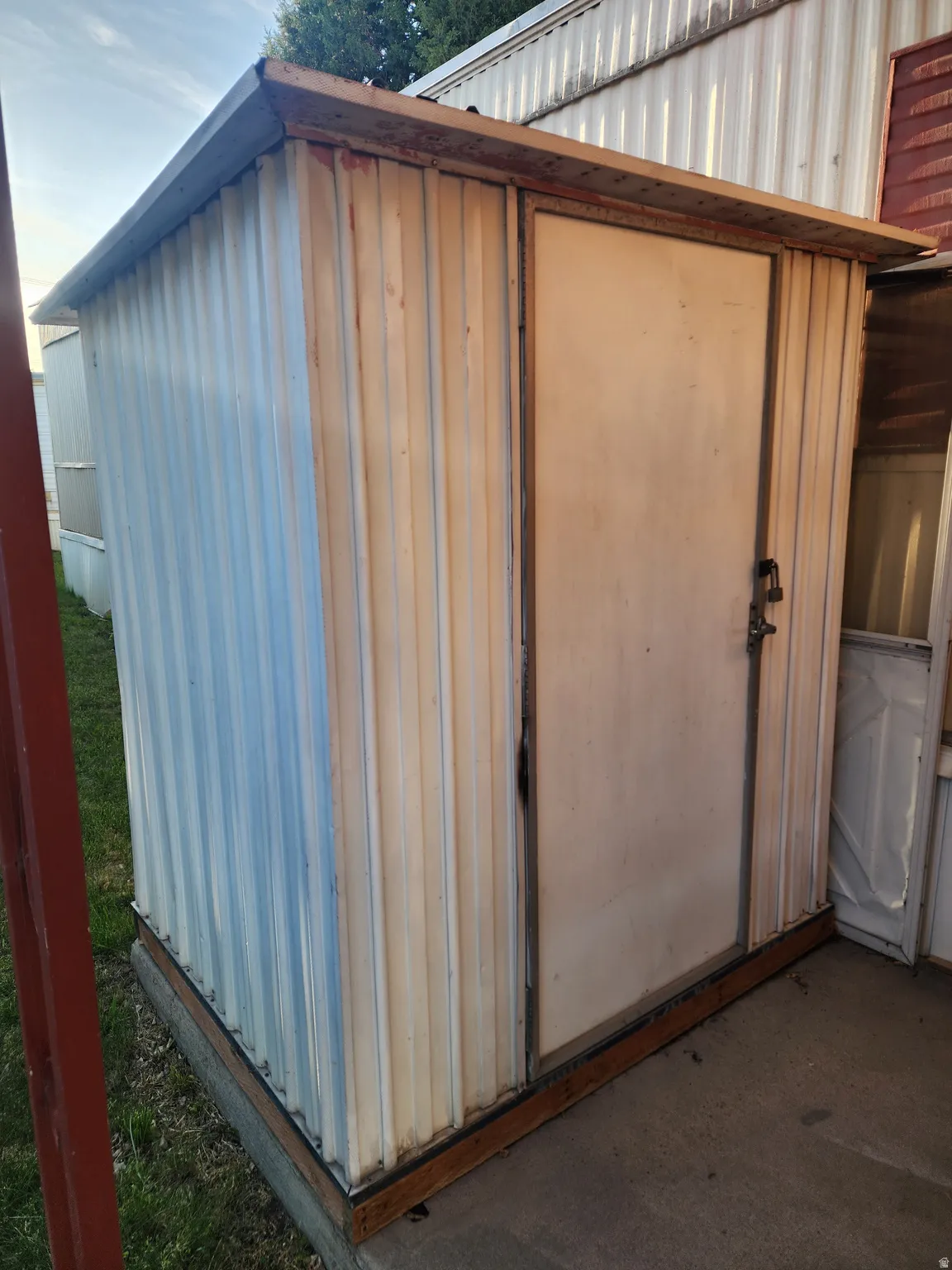 Metal utility shed featuring a flat roof and a single entry door