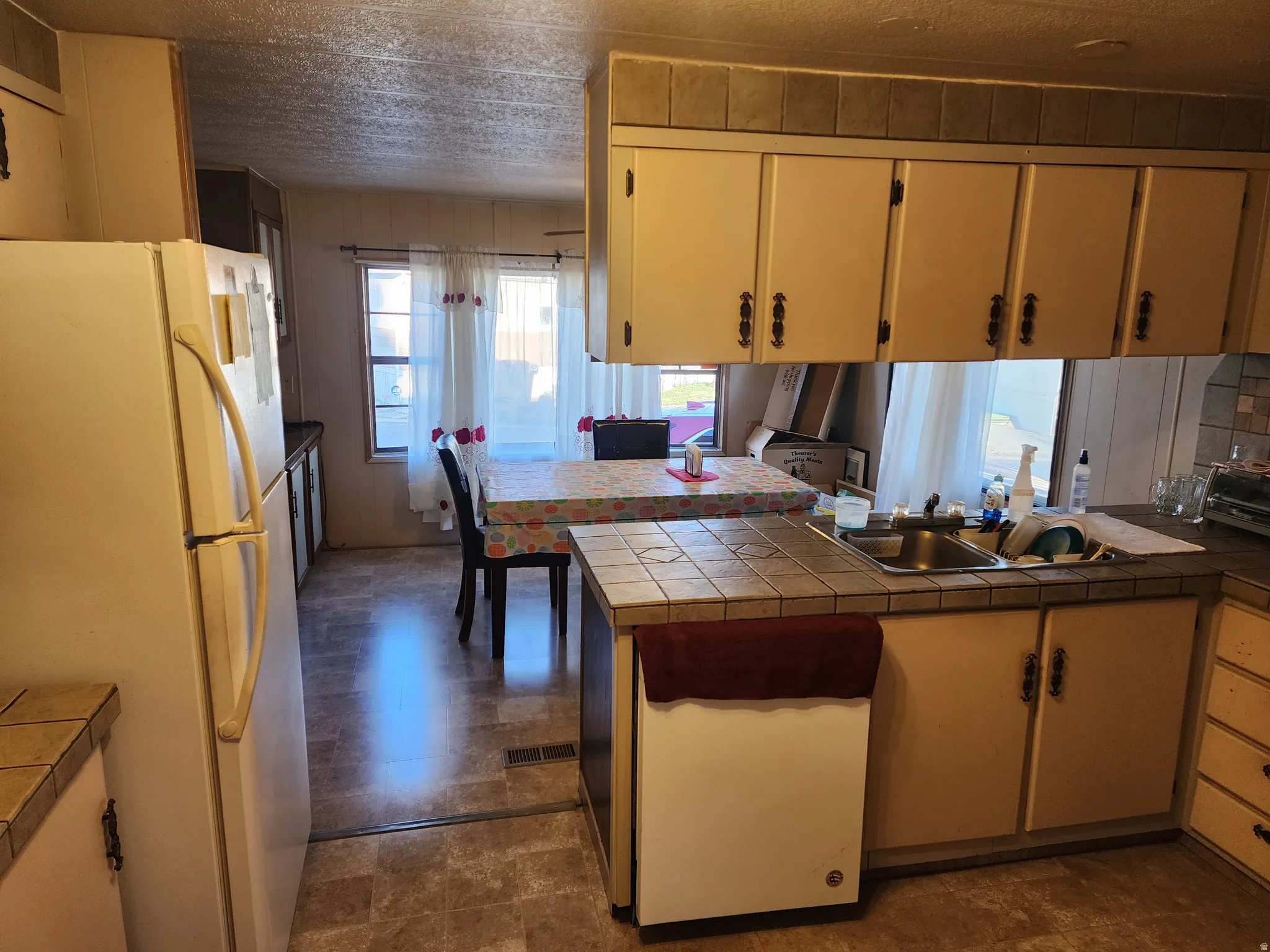 Kitchen featuring tile countertops, stainless steel sink, and light-toned cabinetry