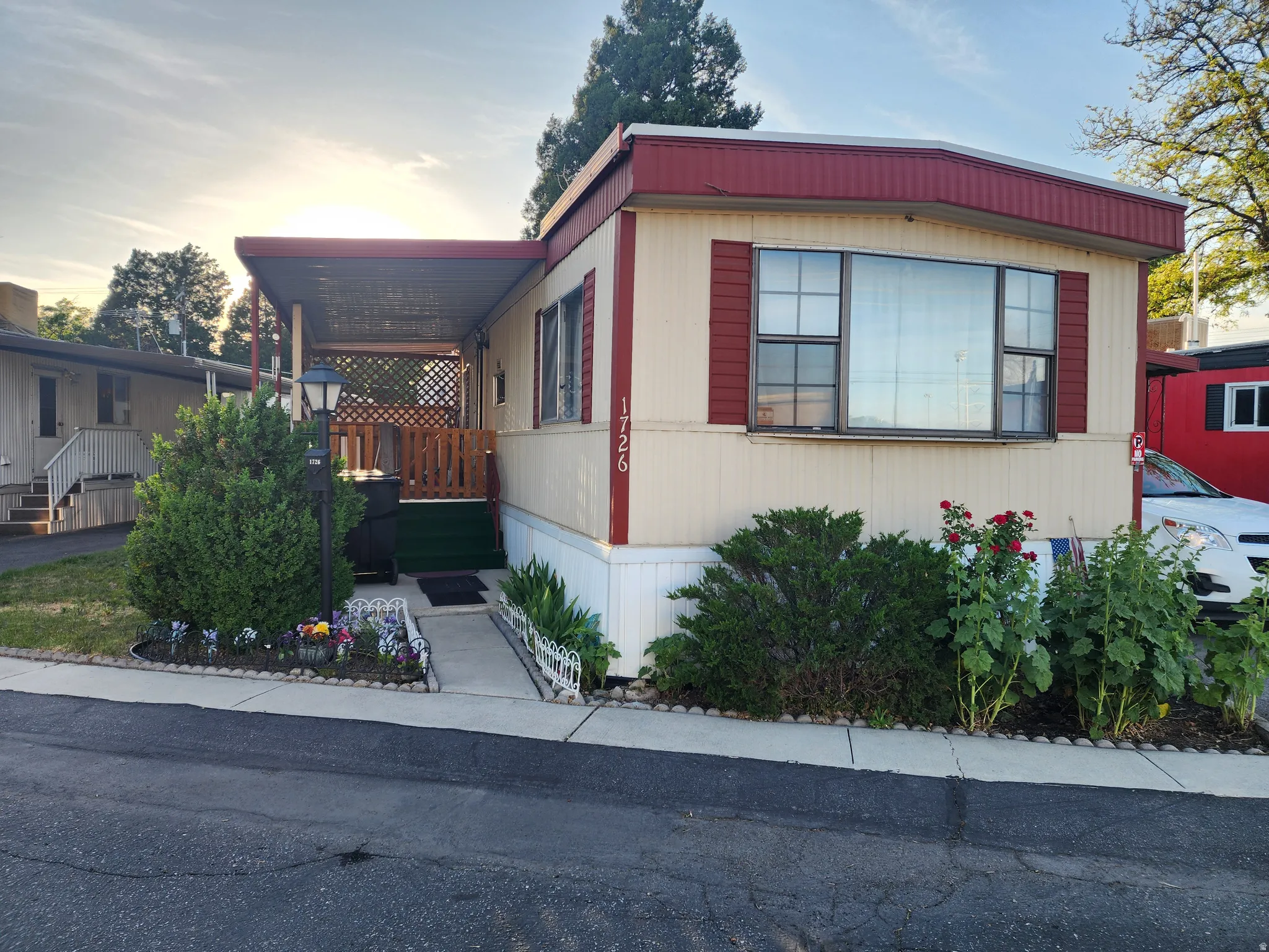 Exterior featuring a covered porch with wooden railings, a prominent bay window with red shutters, and an awning over the entrance