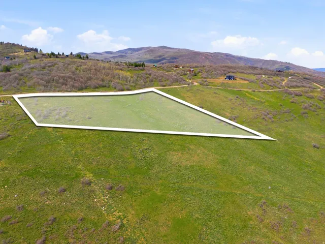 Expansive parcel of land with a rectangular outline, featuring a gentle slope and partial grass coverage