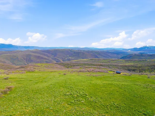 Expansive green acreage featuring distant mountain ranges and a solitary structure