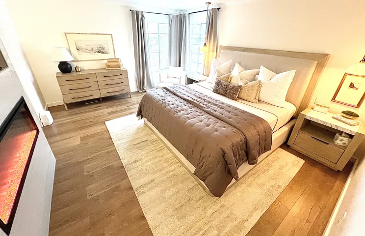 Spacious room featuring wood-finish flooring, a built-in fireplace, and a bay window with drapes