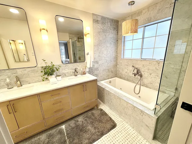 Luxurious bathroom featuring a dual vanity with a light wood-finish cabinet, quartz countertop, and integrated sinks