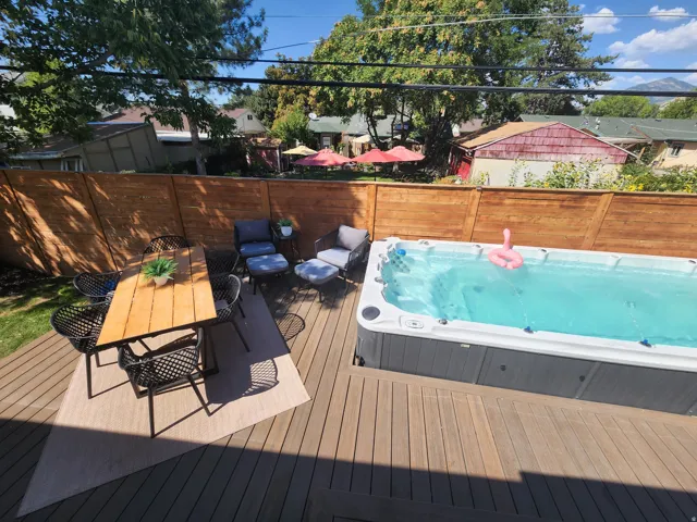 Expansive outdoor living area featuring a large spa, composite decking, and a privacy fence