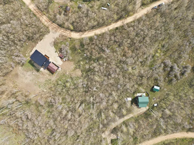 Aerial view of expansive tree-covered grounds with two distinct structures and multiple unpaved access paths