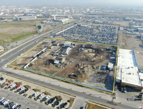 Expansive commercial property featuring clear boundary lines, multiple small structures, direct road access, and proximity to highway infrastructure