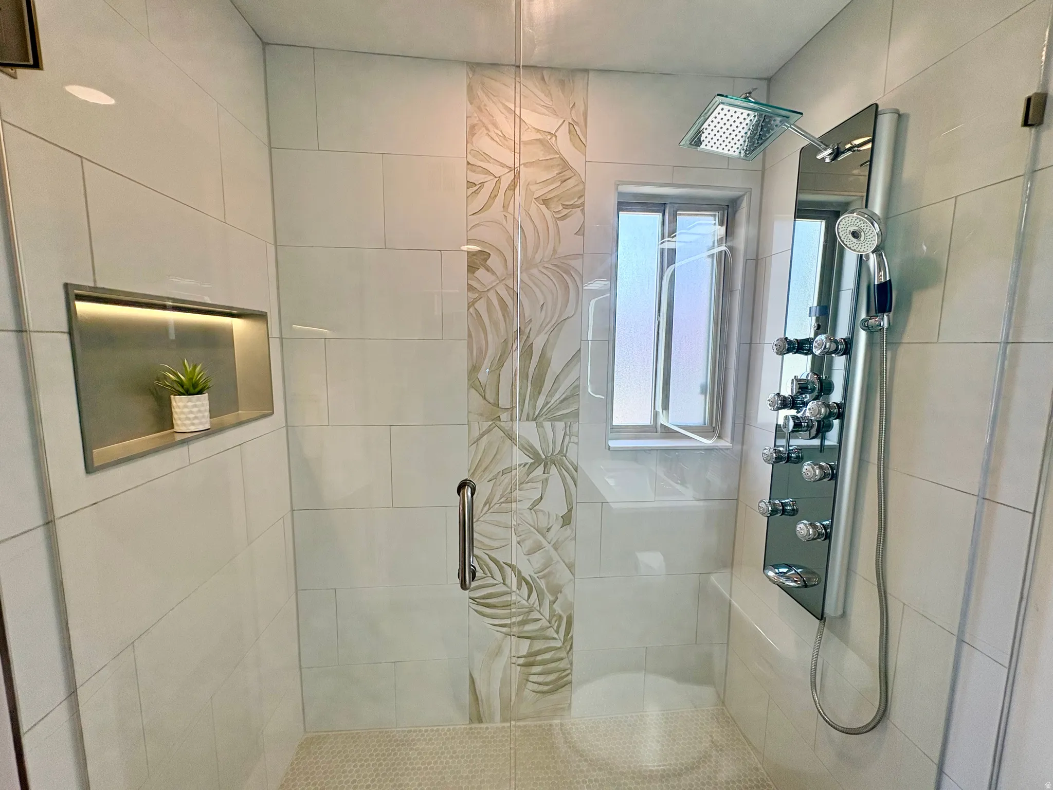 Tiled shower enclosure featuring a multi-function shower panel, square rainfall showerhead, and an integrated bench