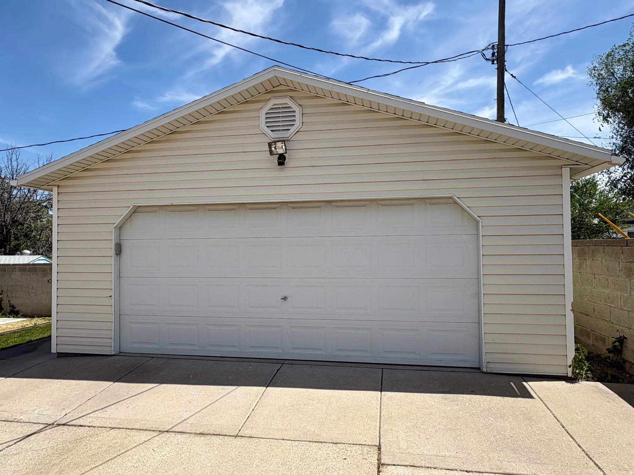 Detached garage with horizontal siding, a gabled roof, and a panel-style garage door