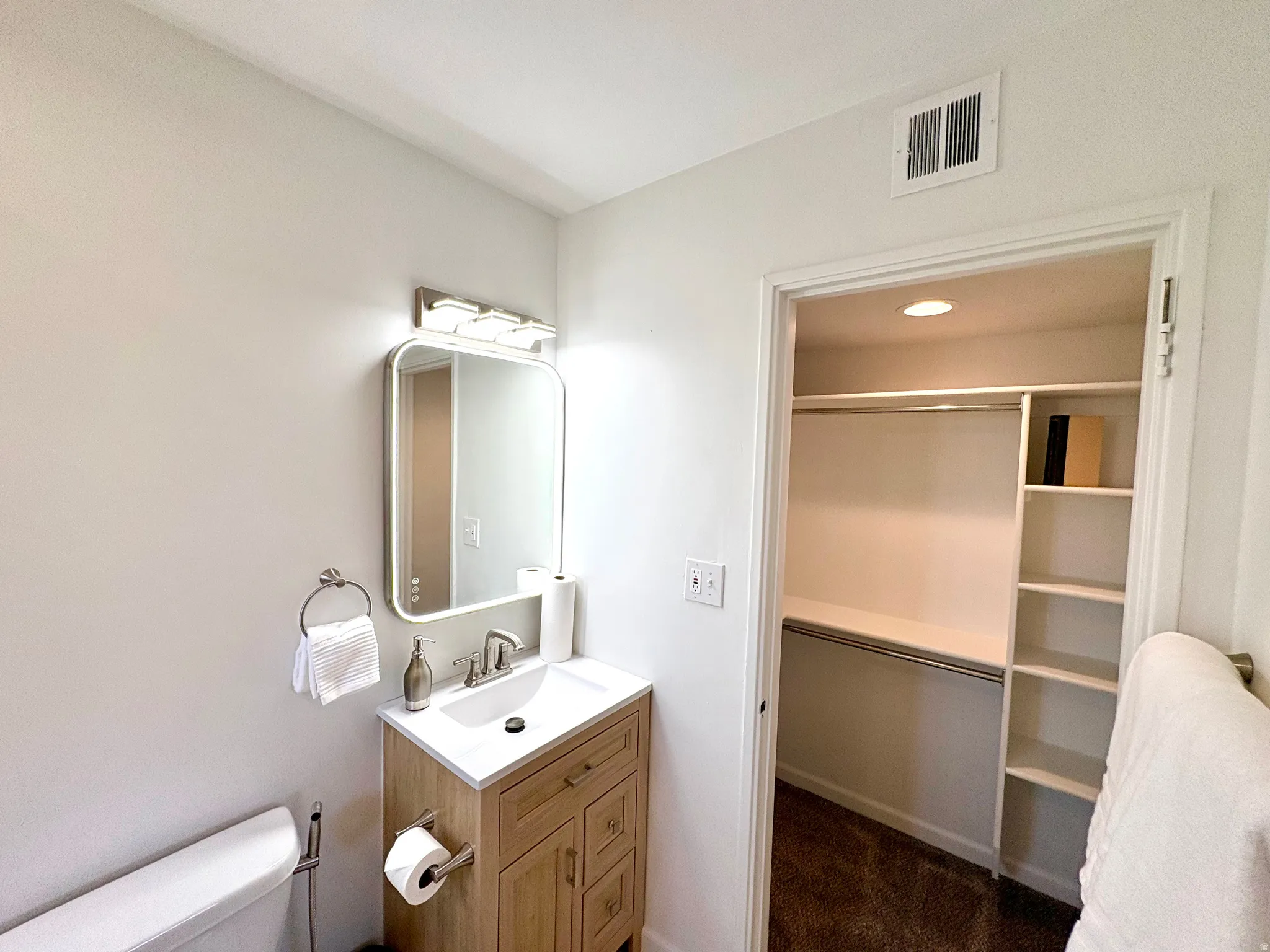 Bathroom vanity featuring a white rectangular sink, chrome-finish faucet, and wood-finish cabinetry