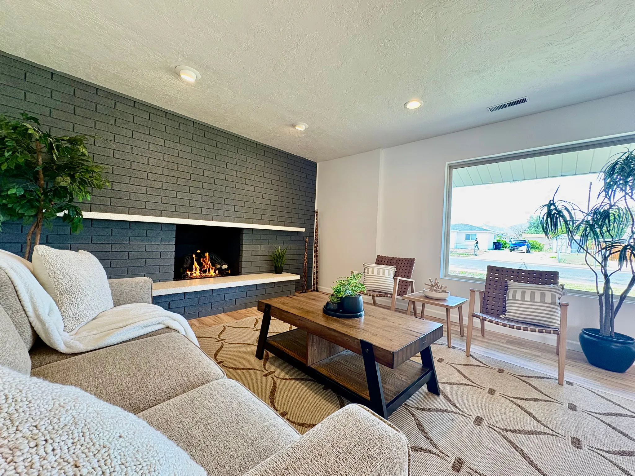 Living area featuring a floor-to-ceiling dark brick fireplace with a white mantel and hearth