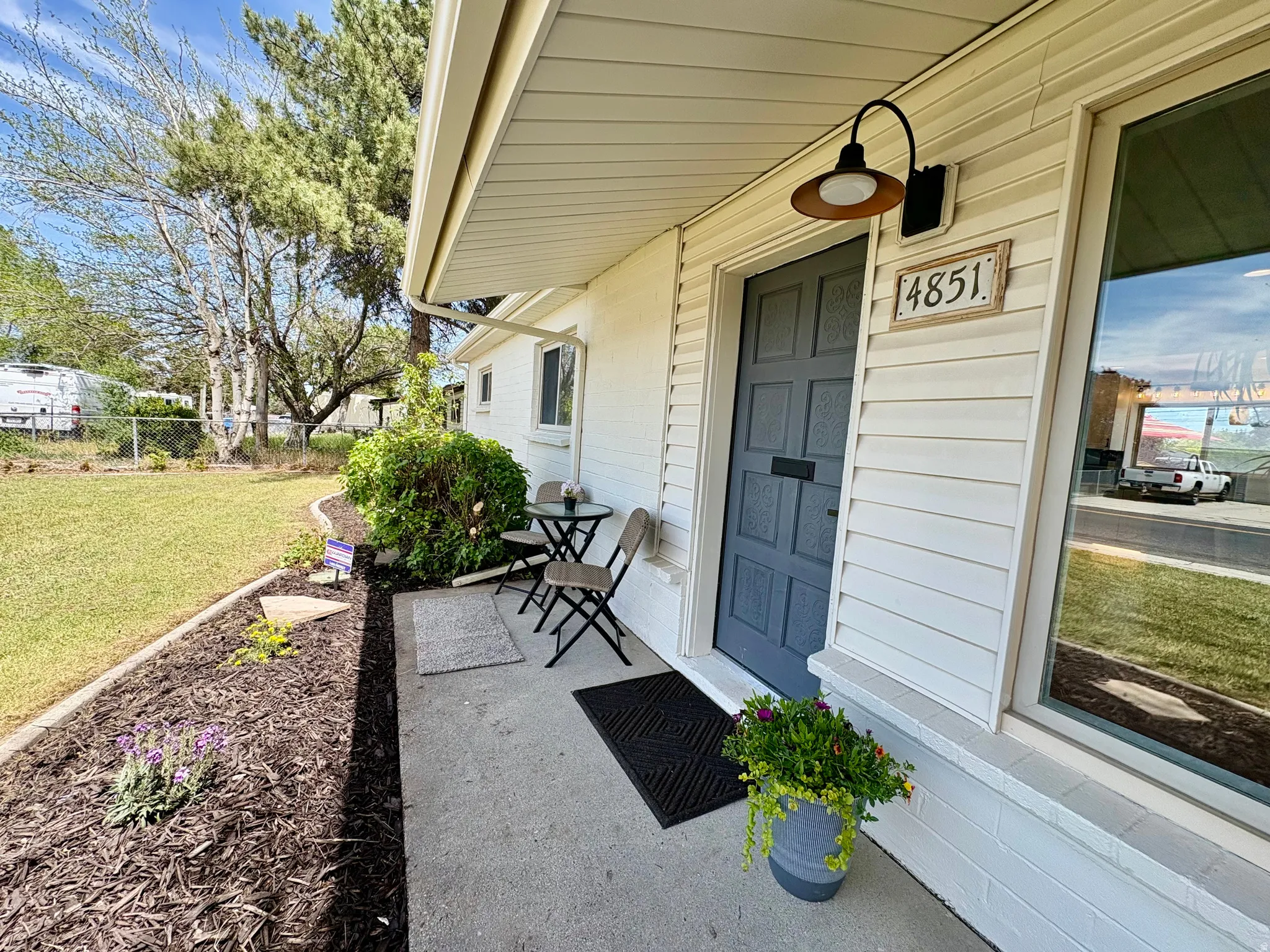 Front entry featuring a dark-colored door with decorative panels, exterior wall lighting, and house numbering