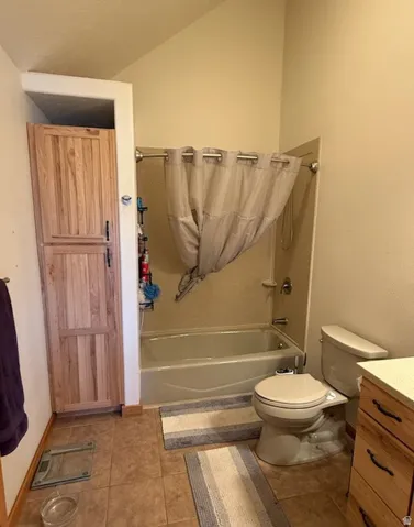 Bathroom featuring a shower-tub combination, tiled flooring, and a built-in wood-finish storage cabinet