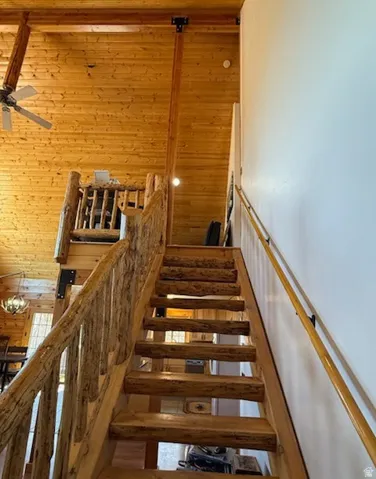 Wood-finish staircase with rustic log railings and a smooth wood handrail
