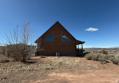 Log cabin exterior featuring a prominent A-frame design, triangular upper-level windows, a covered front porch, and horizontal log siding