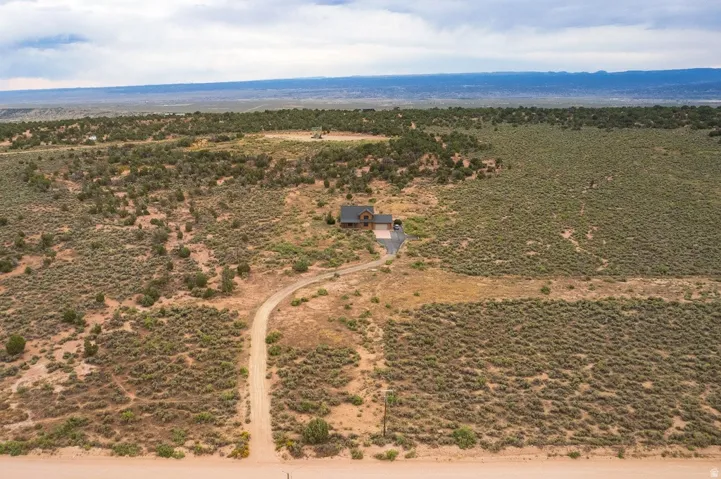 Expansive land parcel featuring a detached residence, gravel driveway, and surrounding natural vegetation
