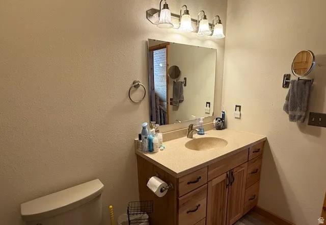 Bathroom featuring a light-toned vanity with a built-in sink, wood-finish cabinetry, and a large wall-mounted mirror