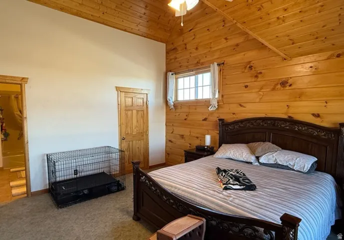 Room featuring natural wood plank walls, vaulted wood plank ceiling, and a ceiling fan