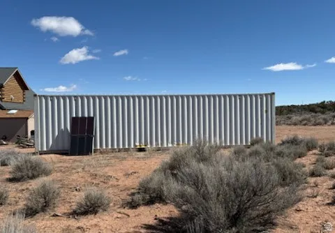 Corrugated metal storage container featuring a gray finish and a two-panel door