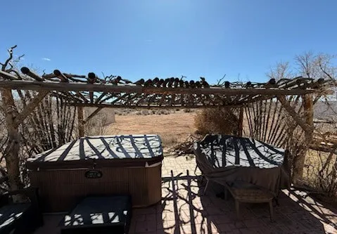 Outdoor pergola structure featuring natural wood and a tiled patio base