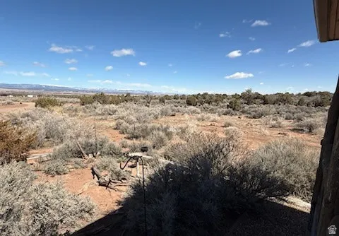 Expansive desert landscape under a clear blue sky, featuring widespread sagebrush and distant mountains