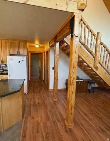 Open-concept interior featuring wood-finish flooring, a log-style staircase with a wood railing, and exposed wood beams