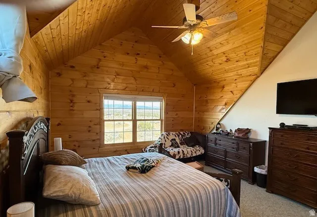 Pine wood paneling throughout, vaulted ceilings, a window with exterior visibility, a ceiling fan, and carpeted flooring