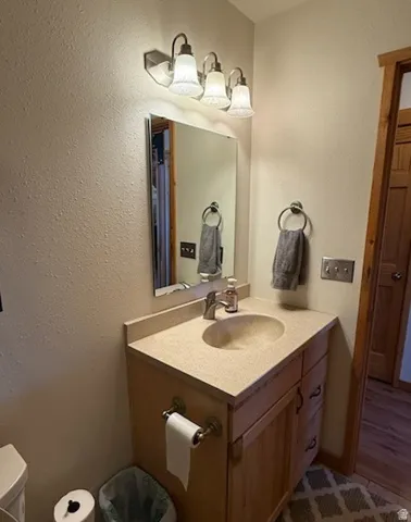 Bathroom vanity featuring a light-toned countertop with an integrated sink, brushed nickel faucet, and a mirror with a three-light vanity fixture