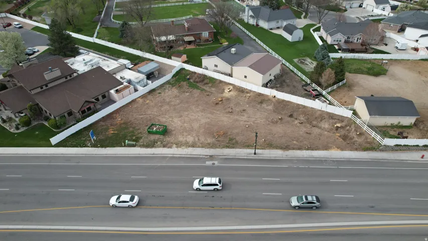 Expansive cleared lot bordered by a white picket fence, featuring a street-front position with direct road access